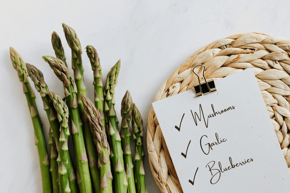 Bunch of asparagus and anti inflammatory diet food list pdf on straw.